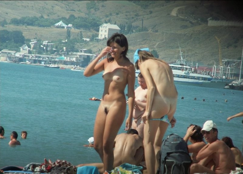 Couple of girls on busy nudist beach 