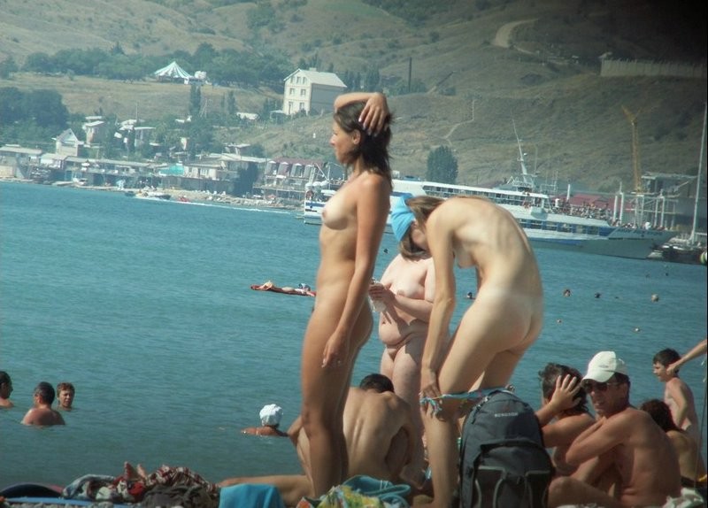 Couple of girls on busy nudist beach 