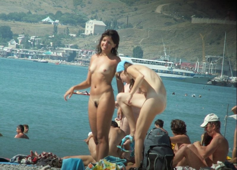 Couple of girls on busy nudist beach 