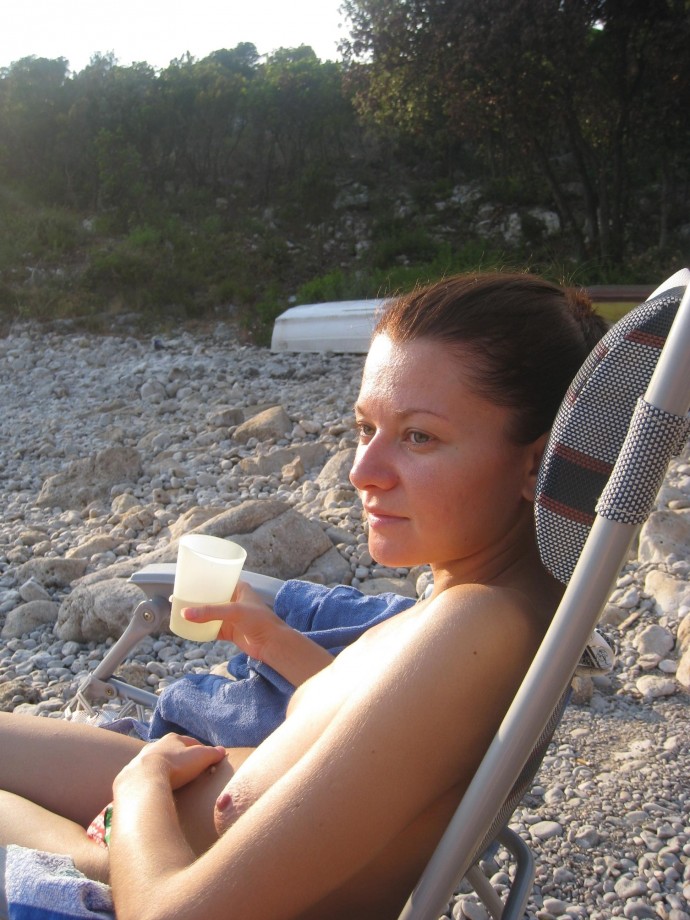 Nudist girls take a drink at the beach 