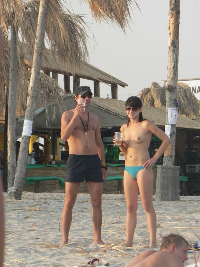 Nudist girls take a drink at the beach 