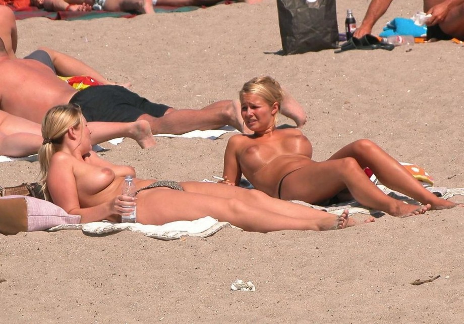 Nudist girls take a drink at the beach 