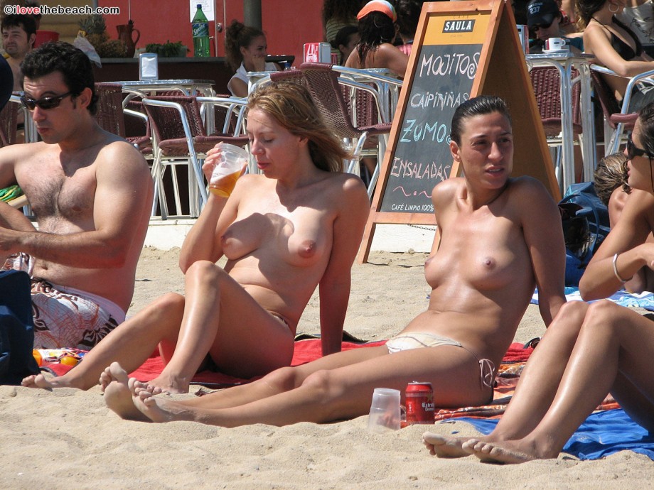 Nudist girls take a drink at the beach 