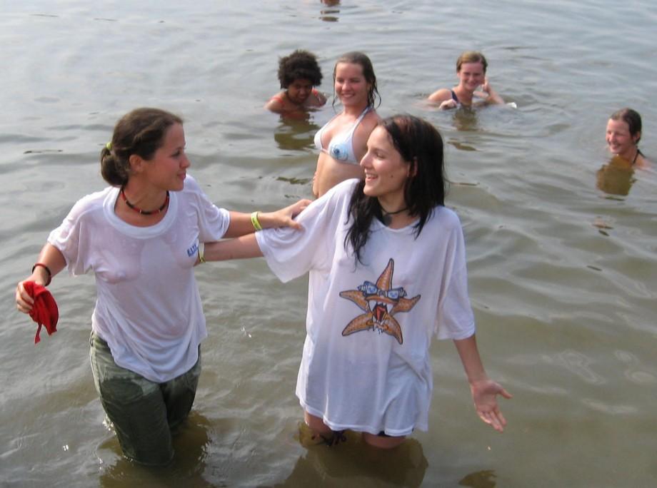 Funny girls on lake in wet shirts