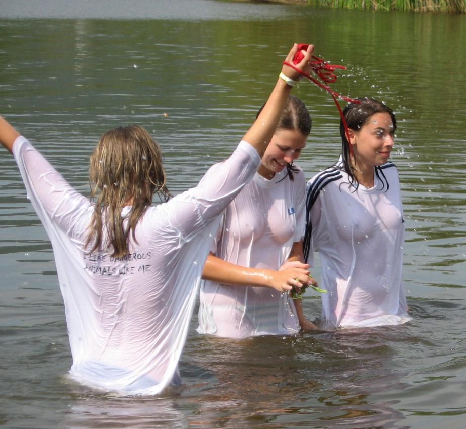 Funny girls on lake in wet shirts