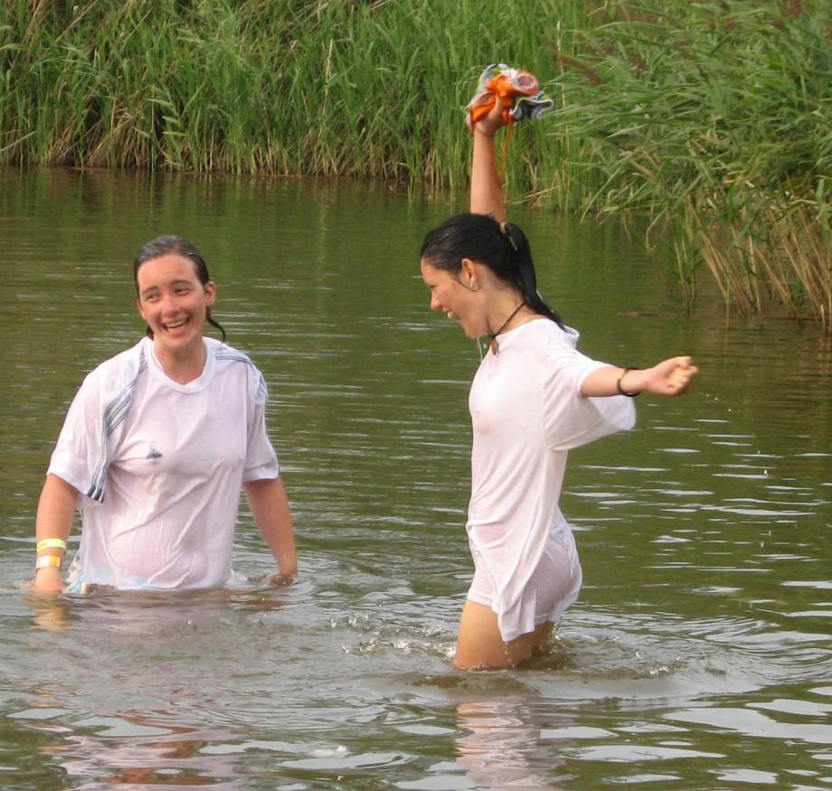 Funny girls on lake in wet shirts