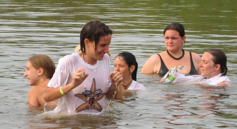 Funny girls on lake in wet shirts