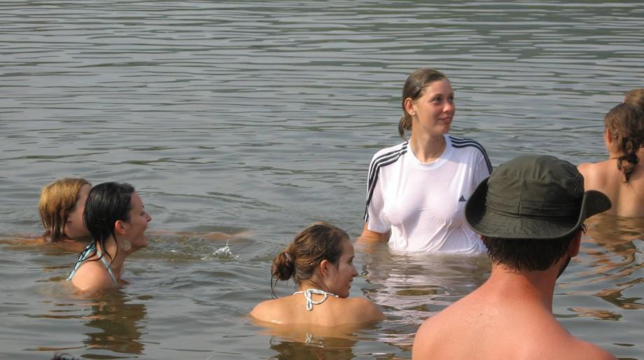 Funny girls on lake in wet shirts