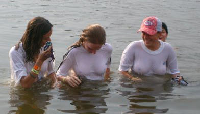 Funny girls on lake in wet shirts