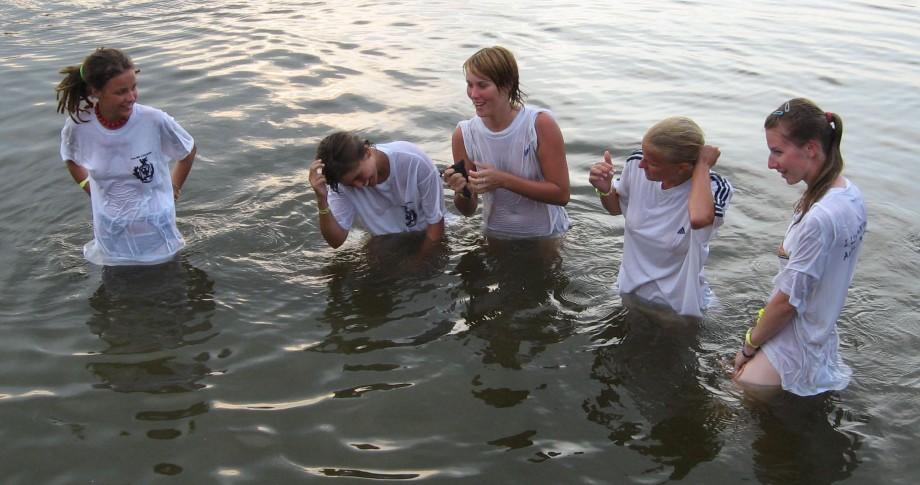 Funny girls on lake in wet shirts