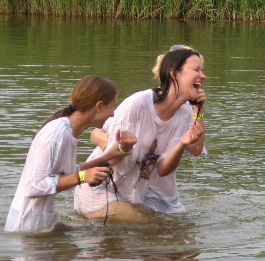Funny girls on lake in wet shirts