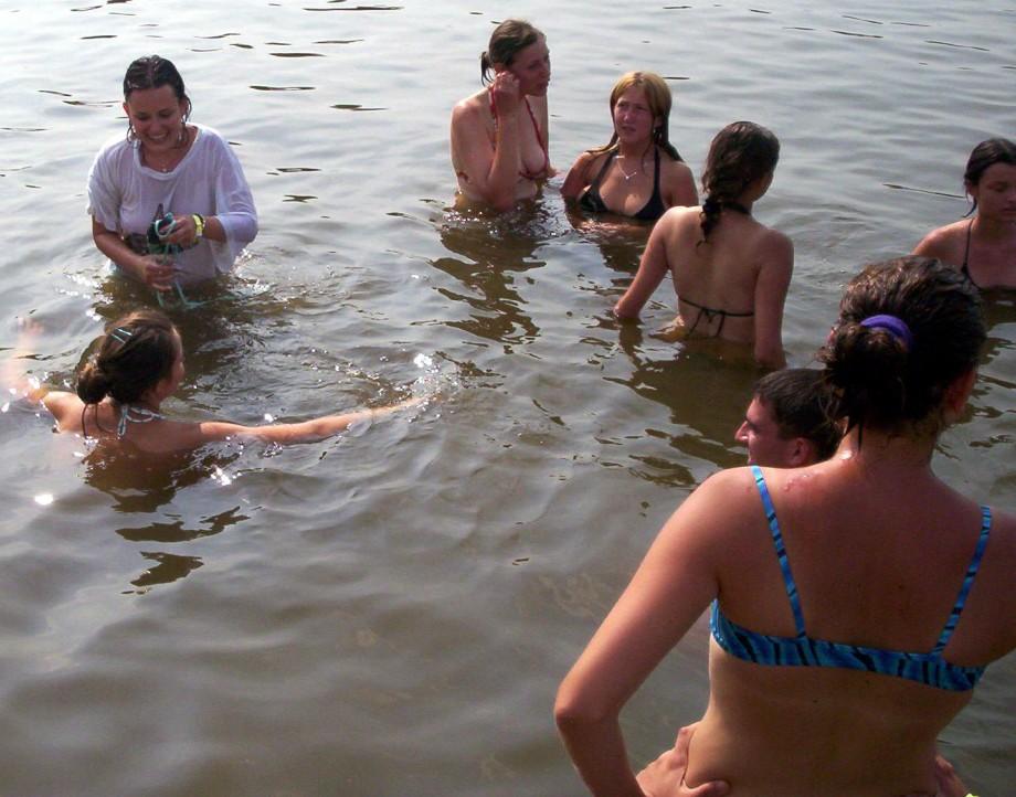 Funny girls on lake in wet shirts