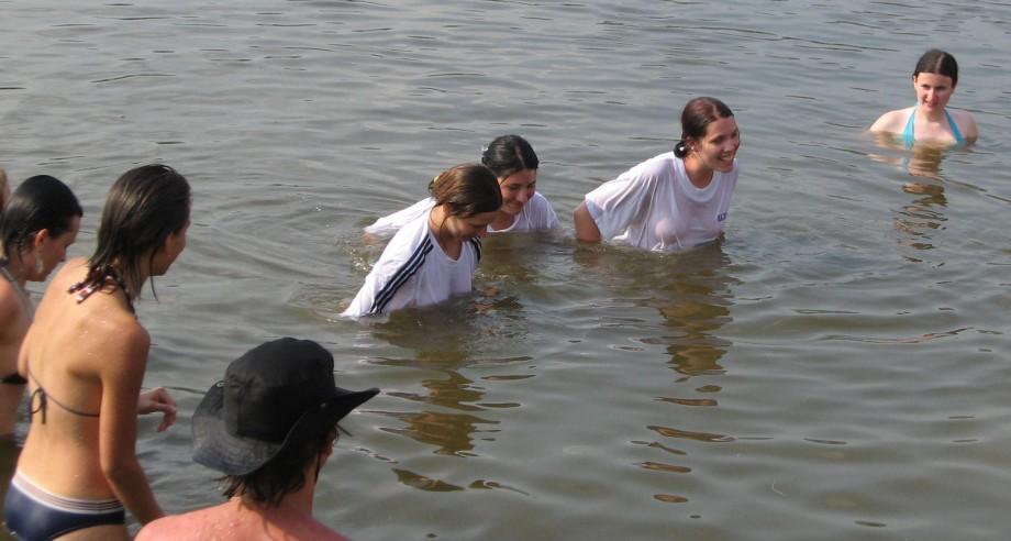 Funny girls on lake in wet shirts