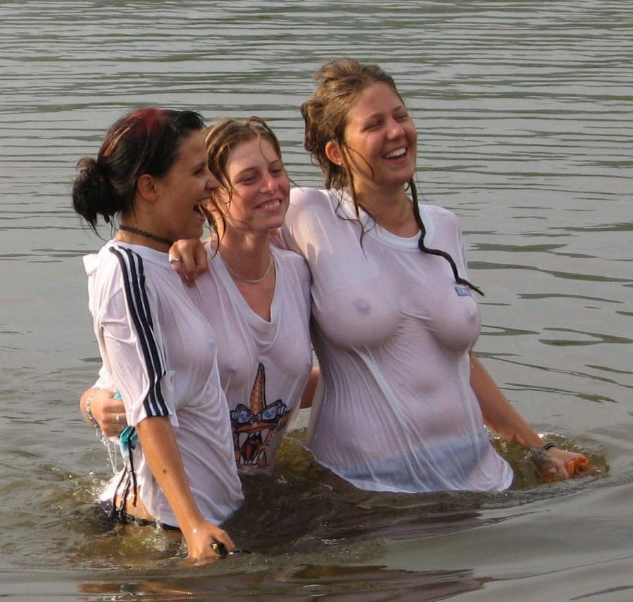 Funny girls on lake in wet shirts