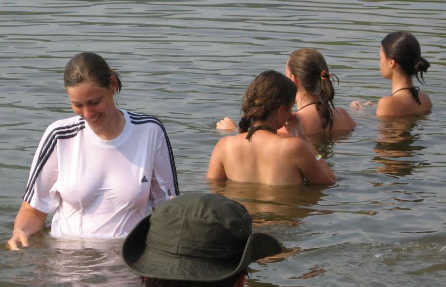 Funny girls on lake in wet shirts