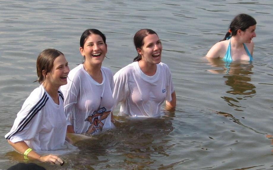 Funny girls on lake in wet shirts