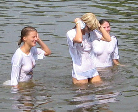 Funny girls on lake in wet shirts