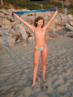 Brunette teen teasing on nude beach 7/46